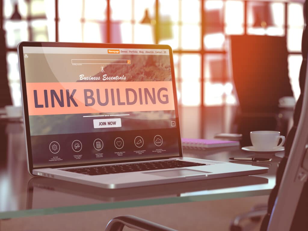 laptop in a coffee shop with "Link Building" written across the screen