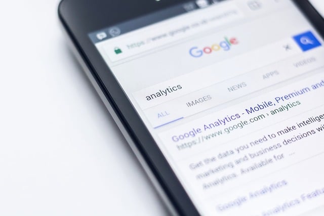Cellphone displaying search for the words 'analytics' as part of essential SEO components.